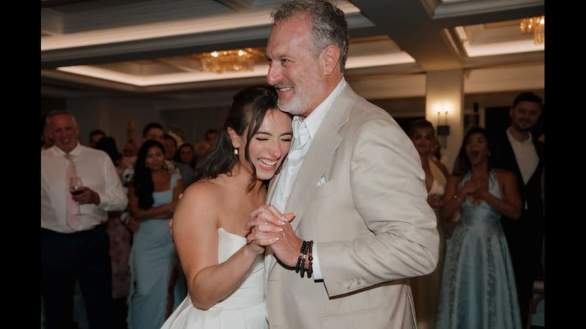 Father and bride dancing at wedding reception during emotional surprise tribute moment