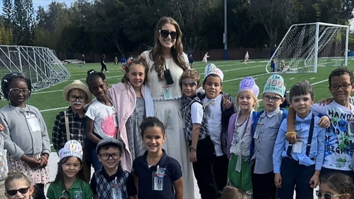 Elementary school teacher emotionally listening to surprise wedding day messages from her students