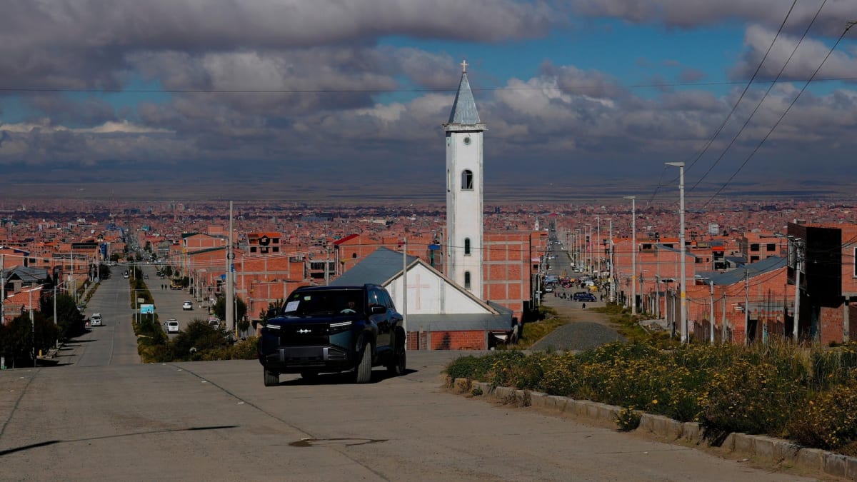 Electric vehicle navigating mountainous streets in El Alto, Bolivia's highest city at sunset