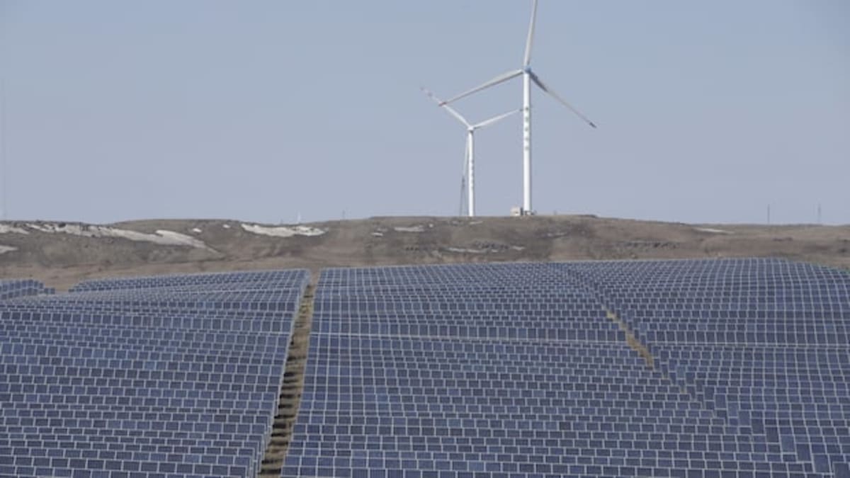 Modern white wind turbines spinning on hillside overlooking Beijing on cloudy day