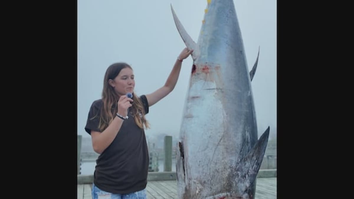 ** Thirteen-year-old Délynn Jacquard standing beside her record-breaking 711-pound bluefin tuna catch in Nova Scotia