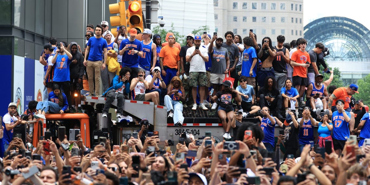 Thousands of Knicks fans in orange and blue celebrating championship parade in Lower Manhattan