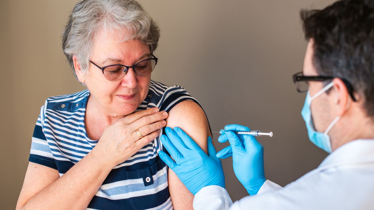 Elderly person receiving flu vaccine injection from healthcare provider in medical setting