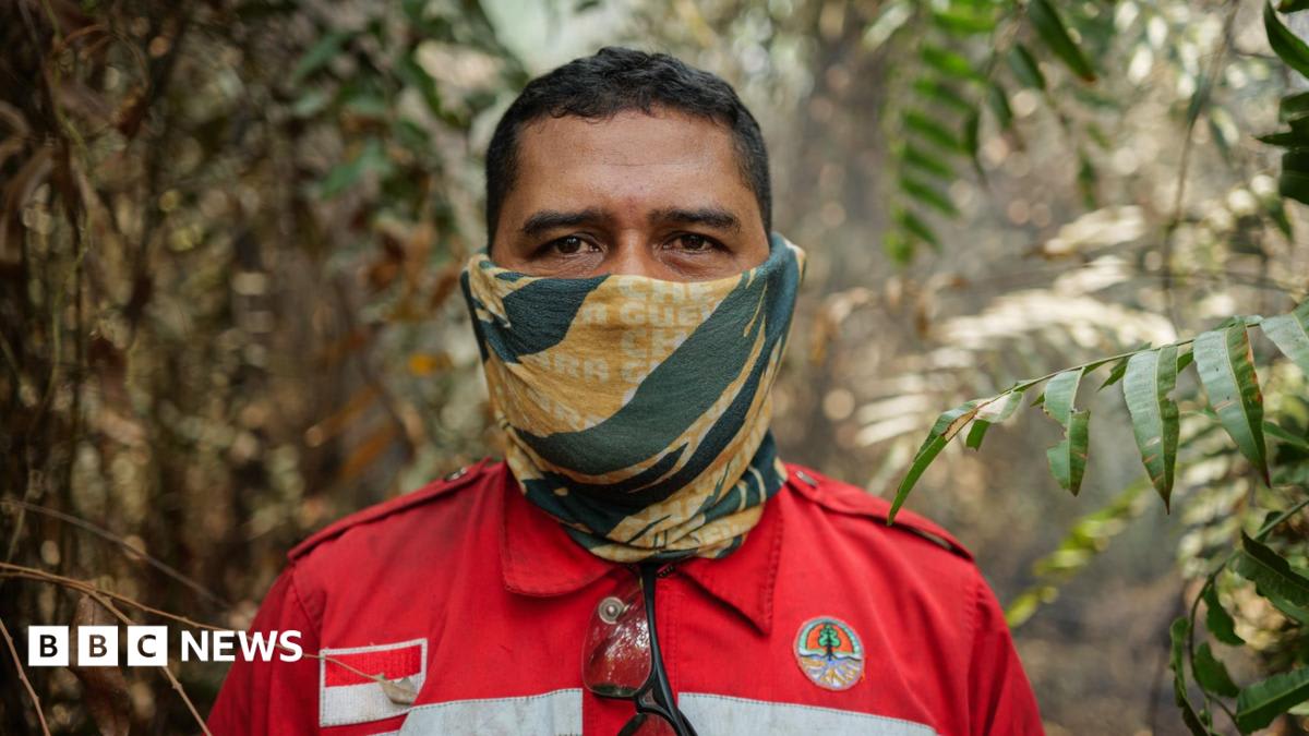 Volunteer firefighter in protective gear battles smoky peat fire in Indonesian Borneo forest