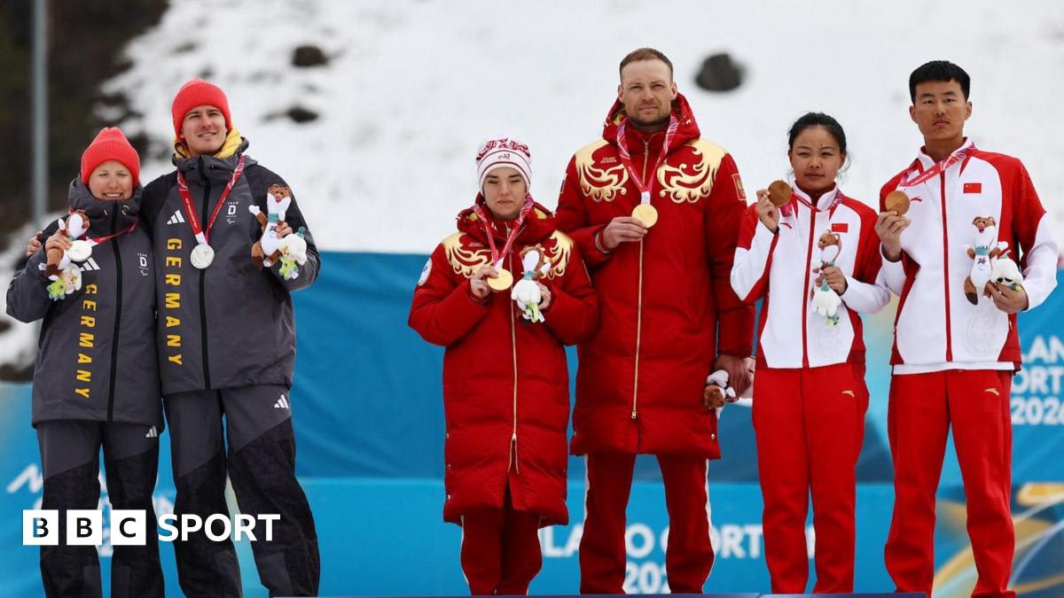 German Paralympic cross-country skiers turning away from Russian flag during medal ceremony