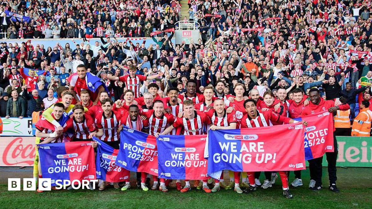 ** Lincoln City soccer players celebrating promotion victory on the field at Reading stadium