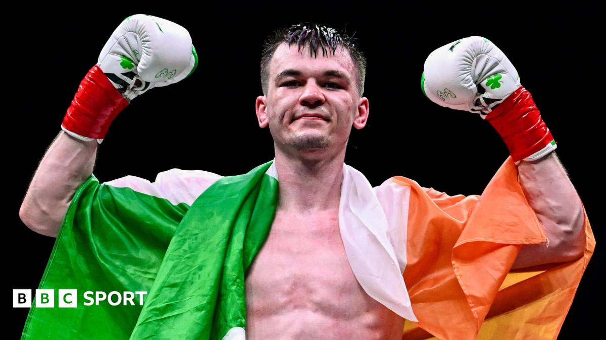 Aaron McKenna celebrates with arms raised wearing championship belt after winning IBF middleweight title in Dublin