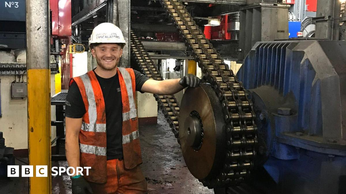 Jay Lovell in football kit standing on pitch, smiling at camera, wearing captain's armband