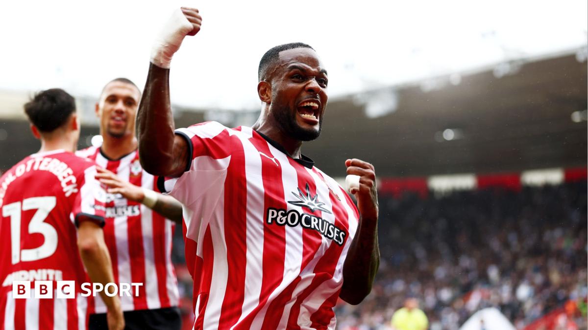 Soccer player Cyle Larin celebrating a goal in Southampton's red and white striped jersey