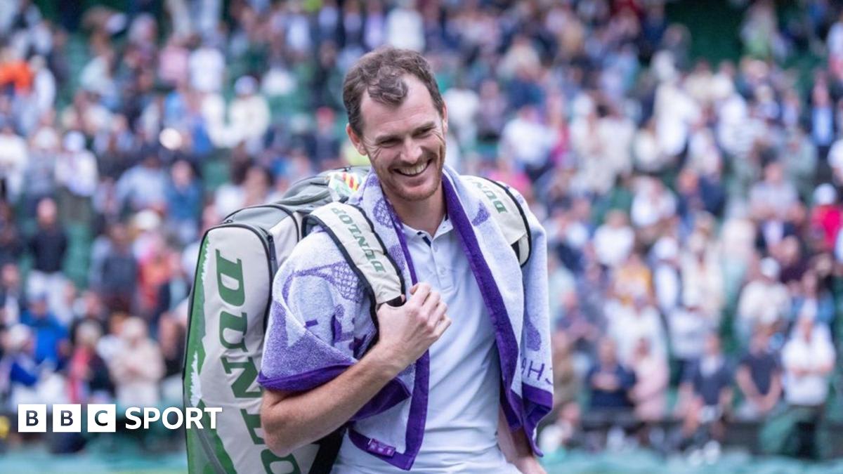 Jamie Murray celebrating on tennis court holding Grand Slam doubles trophy overhead