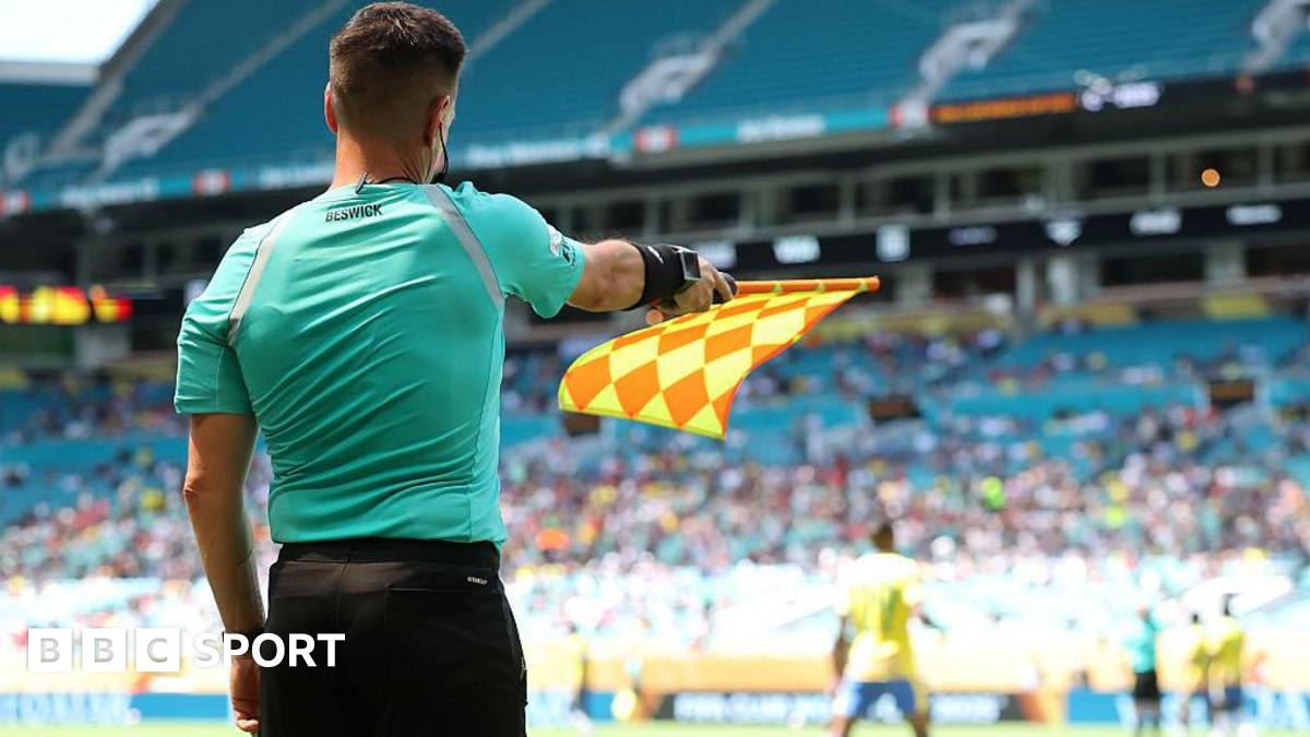 Soccer assistant referee holding electronic flag during professional match with offside technology