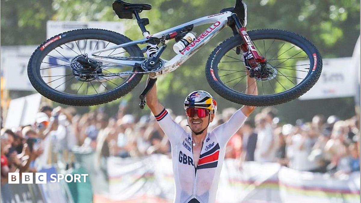 Tom Pidcock raises his mountain bike overhead at finish line in celebration