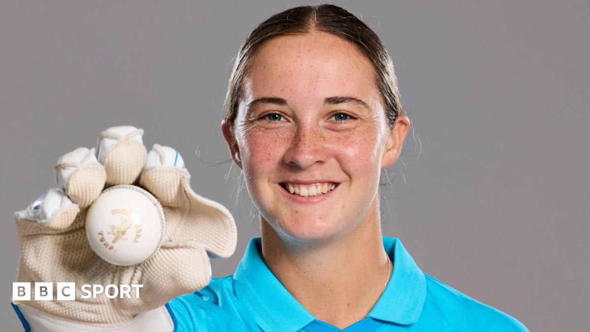 Alice Capsey in England cricket training gear holding wicketkeeping gloves and smiling