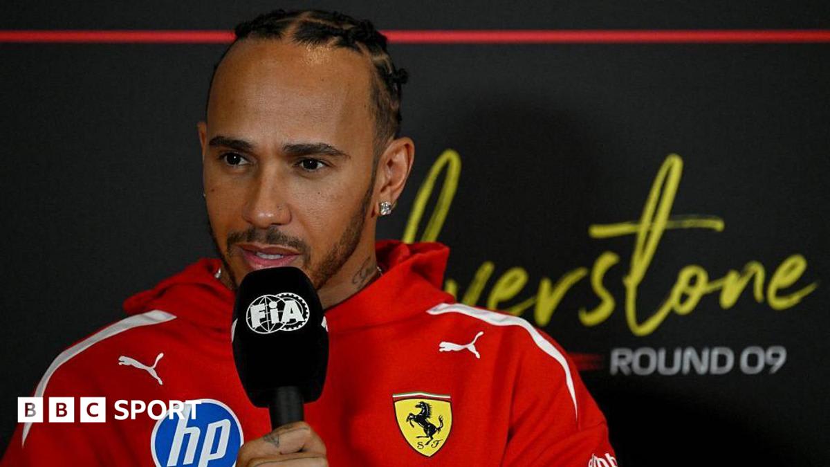 ** Lewis Hamilton in red Ferrari racing suit speaks to media at Silverstone circuit
