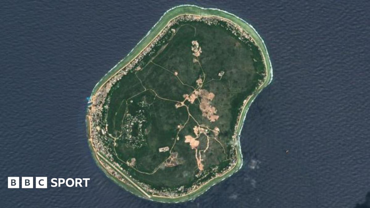 Young children on Nauru island holding soccer balls with ocean coastline visible behind them