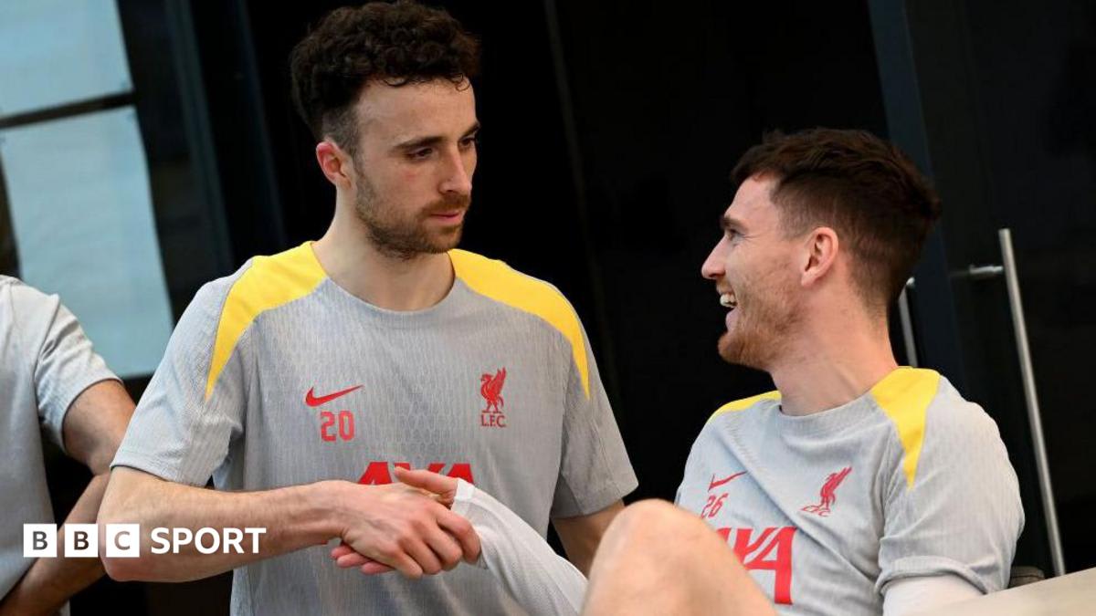 Diogo Jota and Andy Robertson standing together in Liverpool football kit celebrating during a match