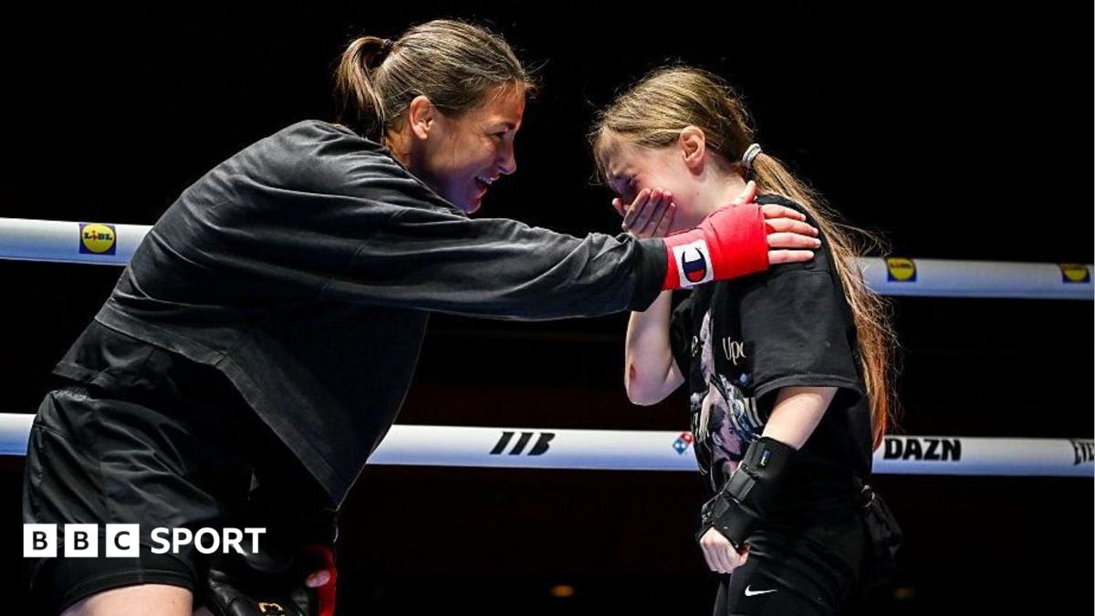 Katie Taylor smiling in boxing gloves during her final fight week media tour in Dublin