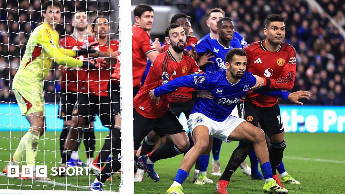Football players crowded in penalty box during corner kick at Premier League match