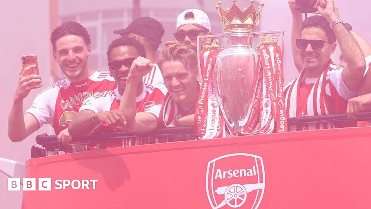 Arsenal players celebrating on open-top bus with Premier League trophy surrounded by cheering fans