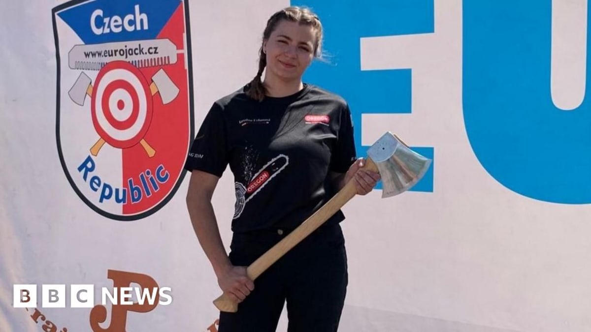 Female athlete chopping through vertical wooden block with axe at outdoor competition