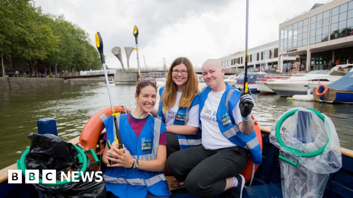 Volunteers in boats pulling trash and debris from Bristol Harbour waterway during cleanup operation