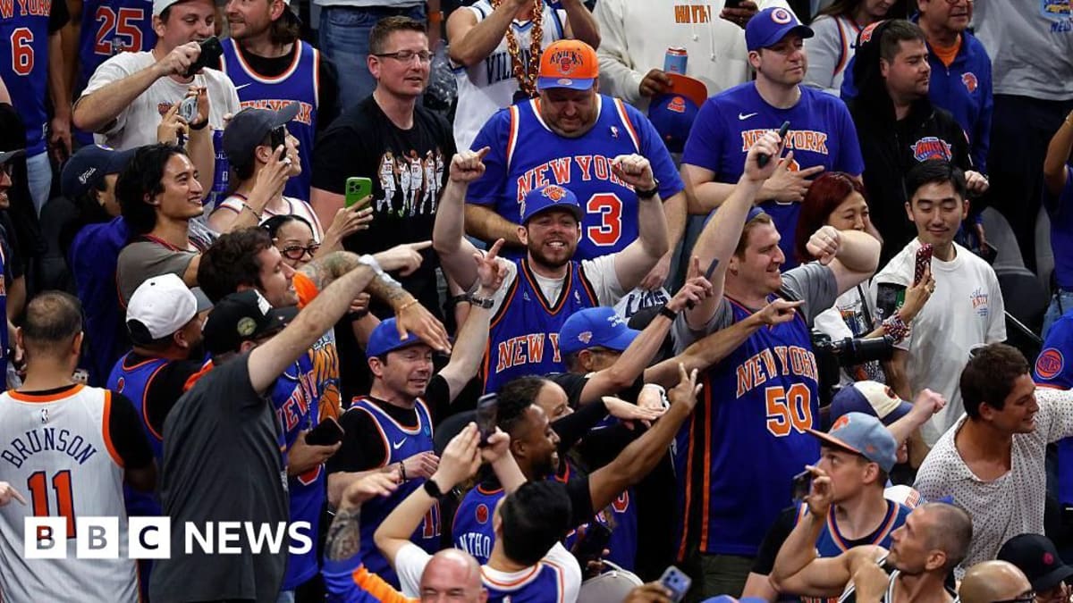 New York Knicks fans cheering enthusiastically at basketball game wearing team colors