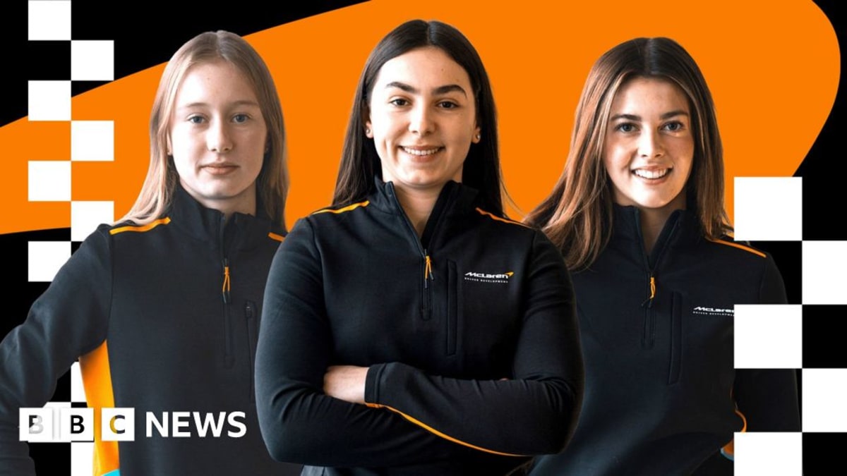 Three young female racing drivers in McLaren team gear standing together smiling