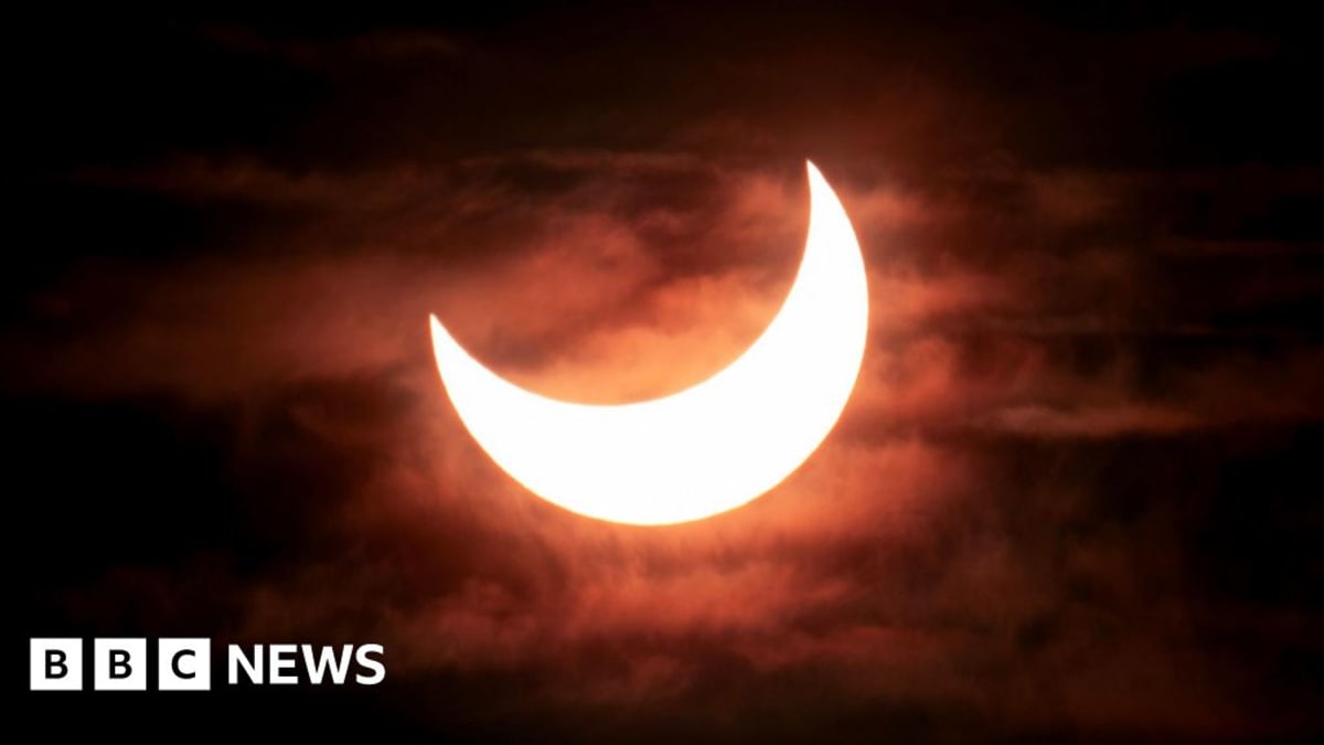 Partial solar eclipse showing moon covering most of the sun's disc against dark sky