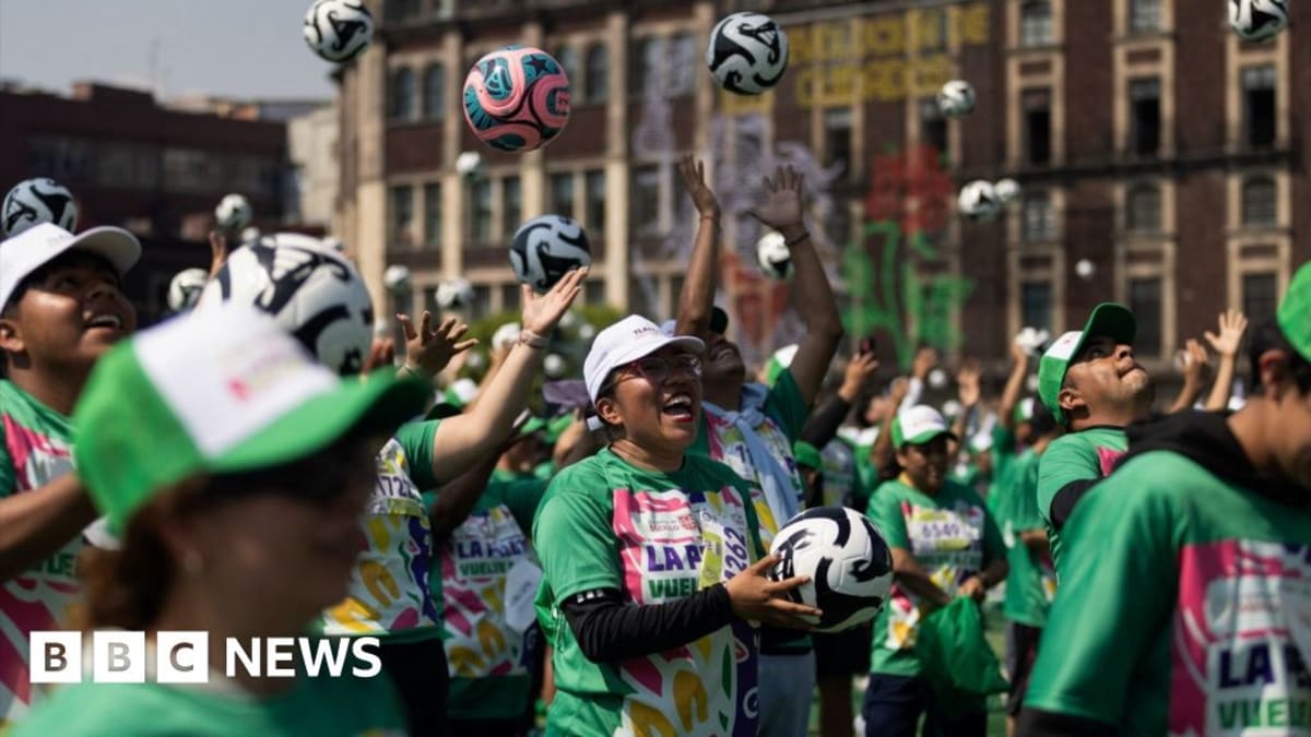 ** Aerial view of thousands of soccer players in matching jerseys filling Mexico City's historic Zócalo plaza during world record training session