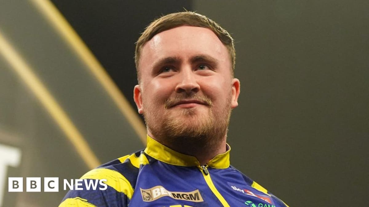 Young darts champion Luke Littler holding trophy after winning world championship title