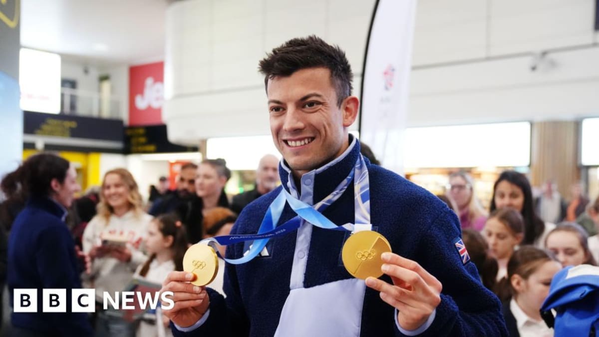 Matt Weston smiling while holding two Olympic gold medals in knitted pouch