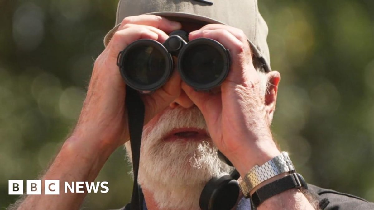 Elderly volunteer Nigel Hewitt smiling outdoors at bird conservation reserve in Devon England