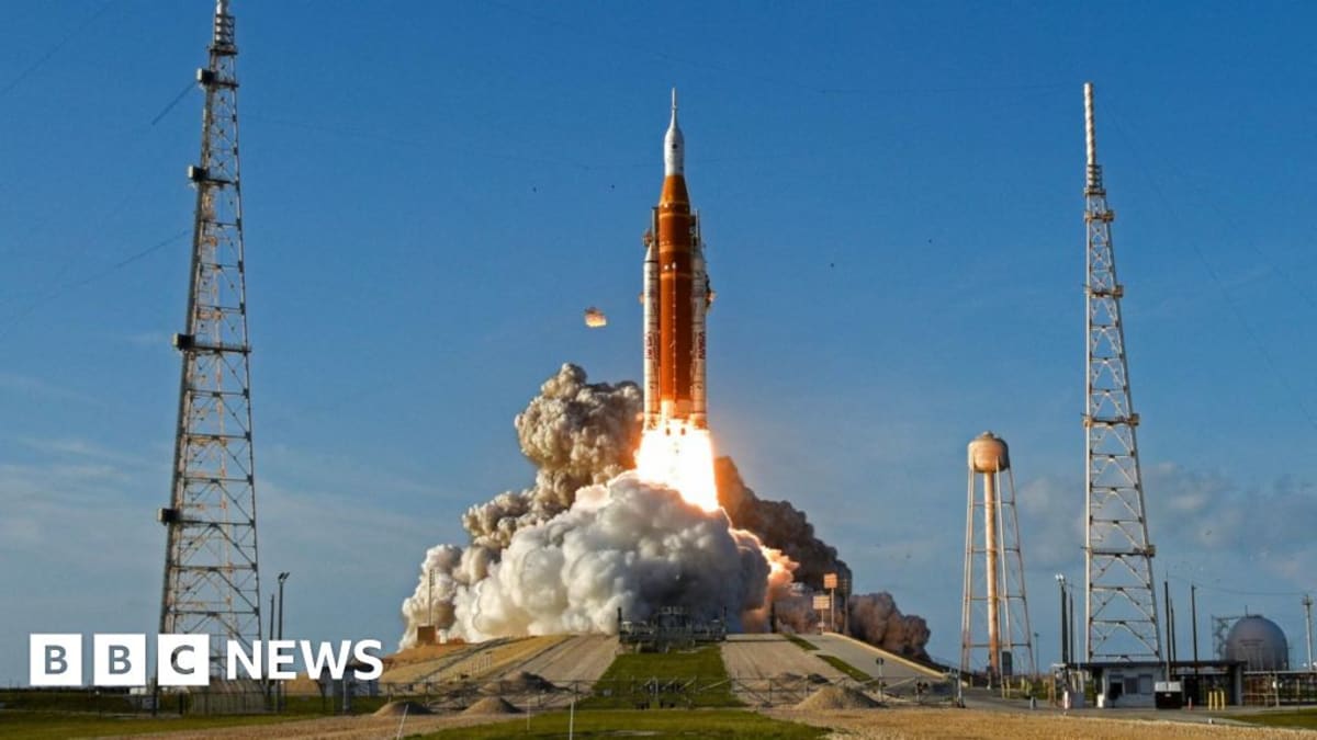 Four Artemis II astronauts in orange spacesuits floating inside Orion capsule near Moon