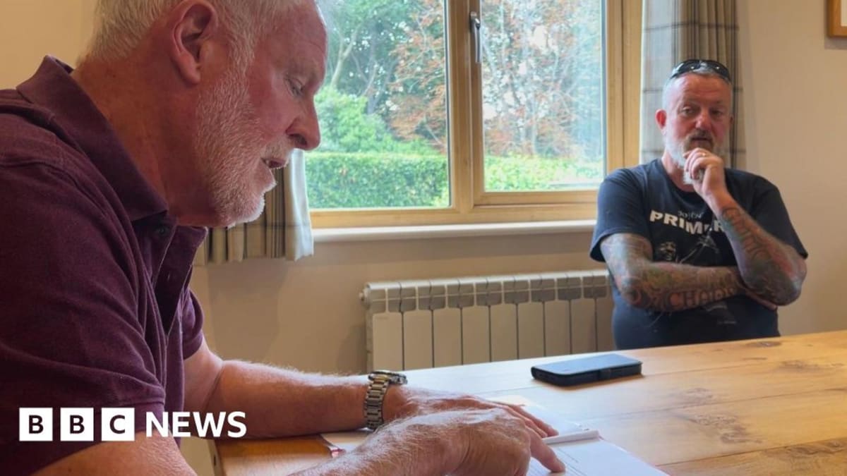 Two men standing together outdoors discussing solar panel plans in Guernsey greenfield site