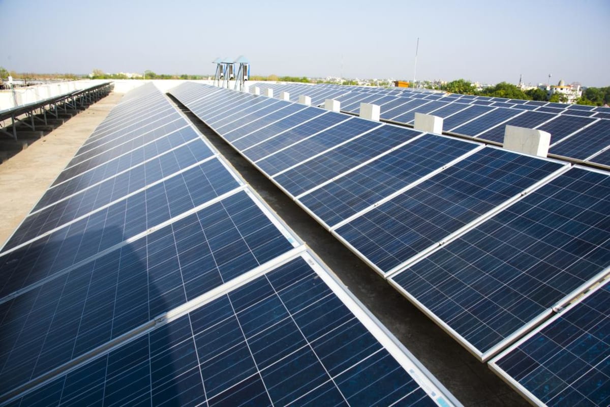 Solar panels and wind turbines against blue sky representing India's renewable energy expansion