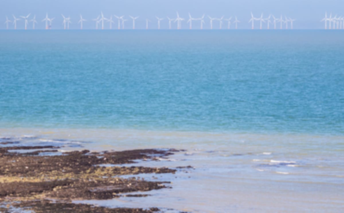 Offshore wind turbines spinning against blue sky generating clean renewable electricity for Britain