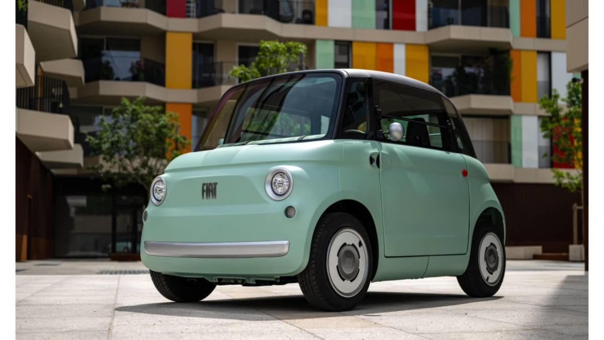 Small white Fiat Topolino electric vehicle with rounded design and compact body parked outdoors