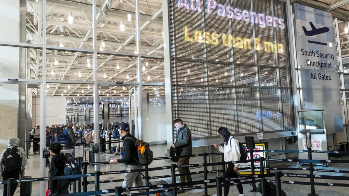 Travelers walking through bright modern airport terminal with high ceilings and natural light