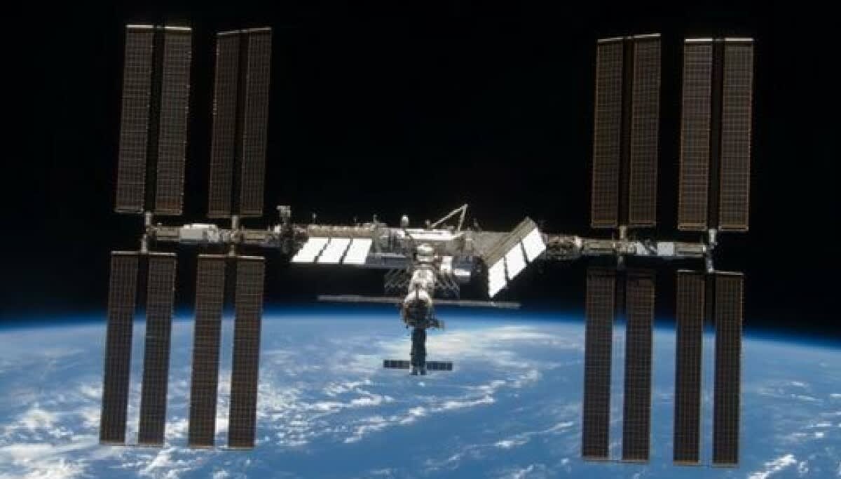 International Space Station orbiting Earth with solar panels extended against the blue planet below