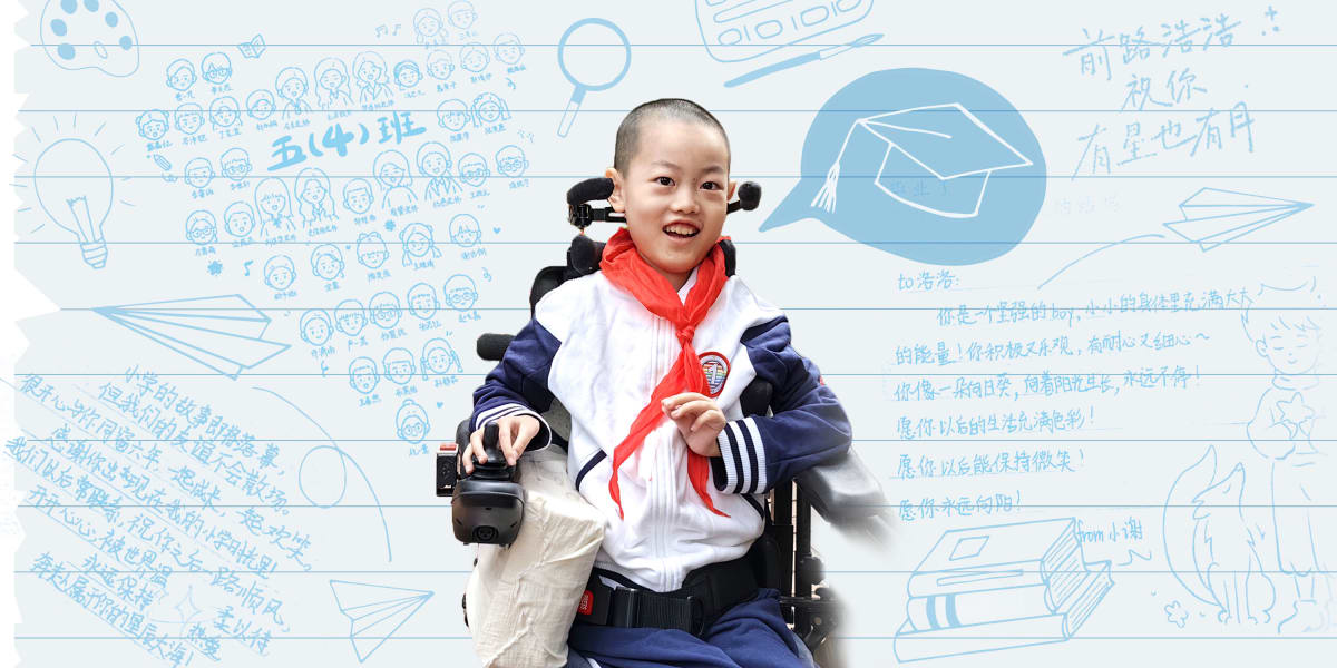 Young boy in electric wheelchair smiling with classmates around him holding yearbook