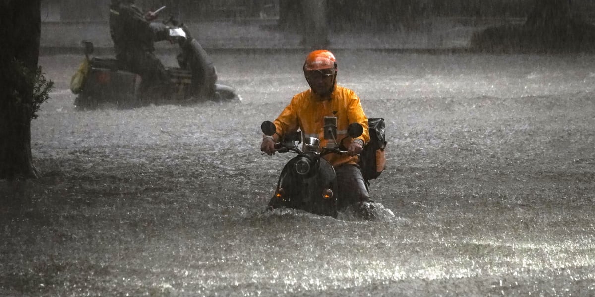 Delivery driver on motorcycle navigating busy city street in China with food delivery bag