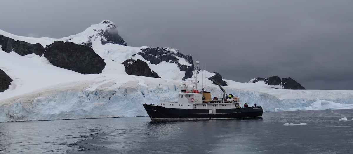 Aerial view of Antarctica's icy landscape with research station buildings under clear blue sky