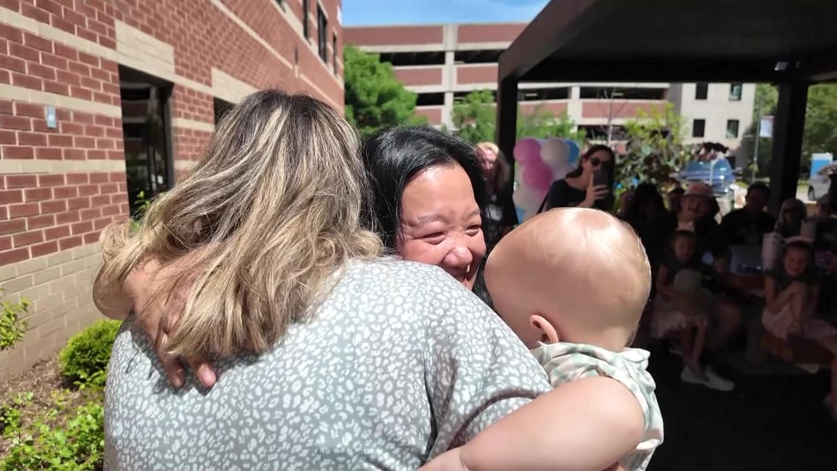 Nurse Keai Morris hugging one-year-old Casper and mother Emily Lena during reunion at Phelps Hospital