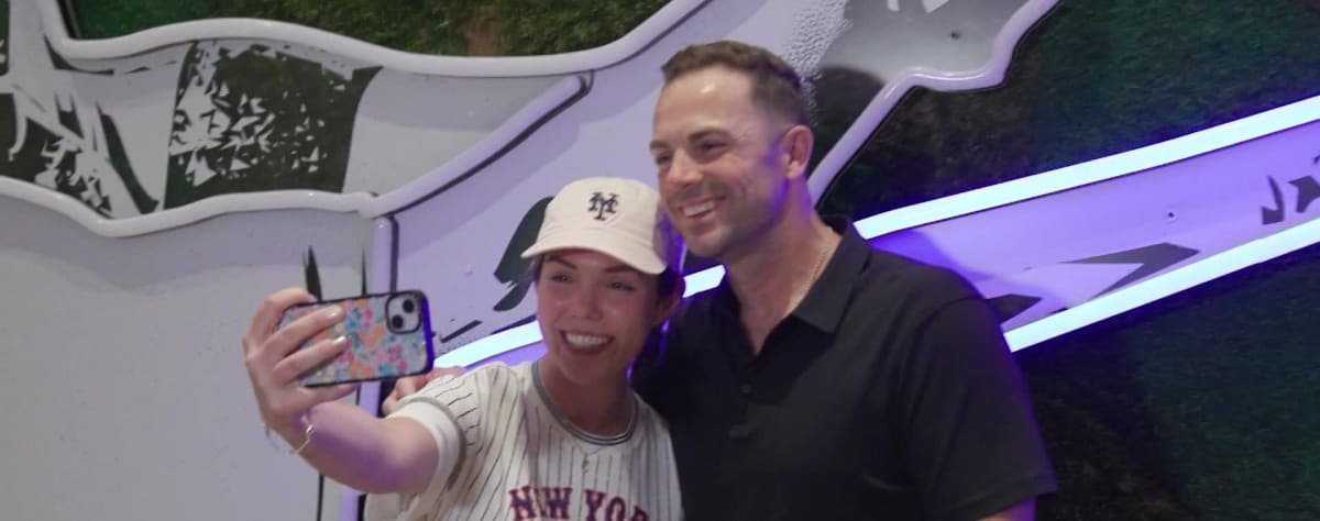 Bridget Rogers stands on baseball field with Mets legend David Wright smiling beside her