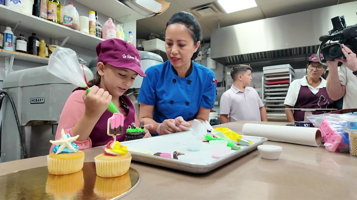 Young girl decorating cupcakes with Suffolk County police officers at local bakery
