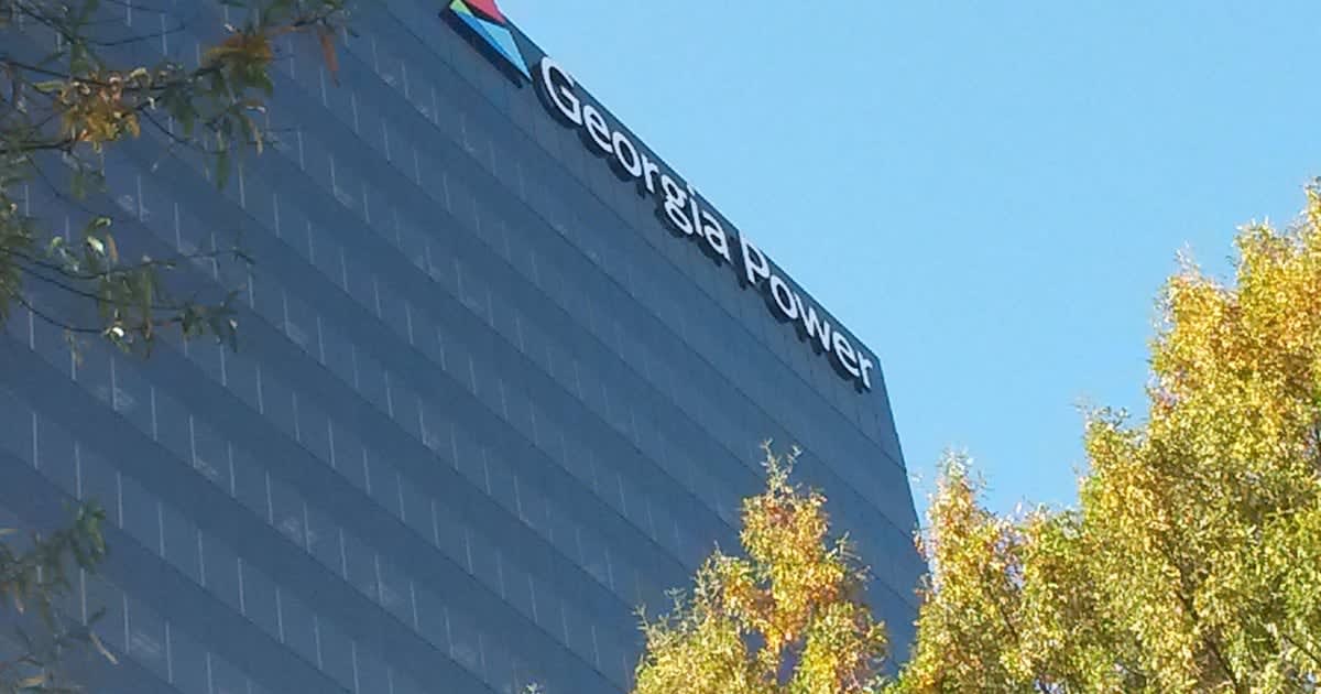 Solar panels installed on commercial building rooftop with Georgia Power transmission lines in background