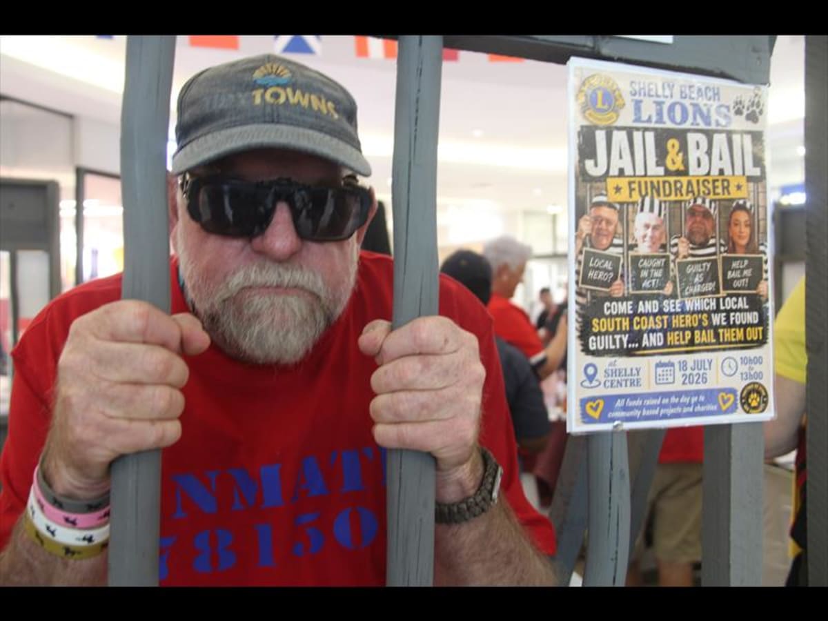 Farmer Scott Kvalsvig stands behind mock jail bars with his dog Florrina during community fundraiser