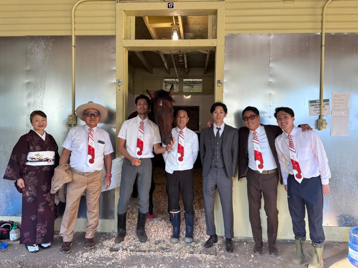 Yuto Kumagai standing beside champion racehorse Forever Young at Belmont Park racetrack in New York