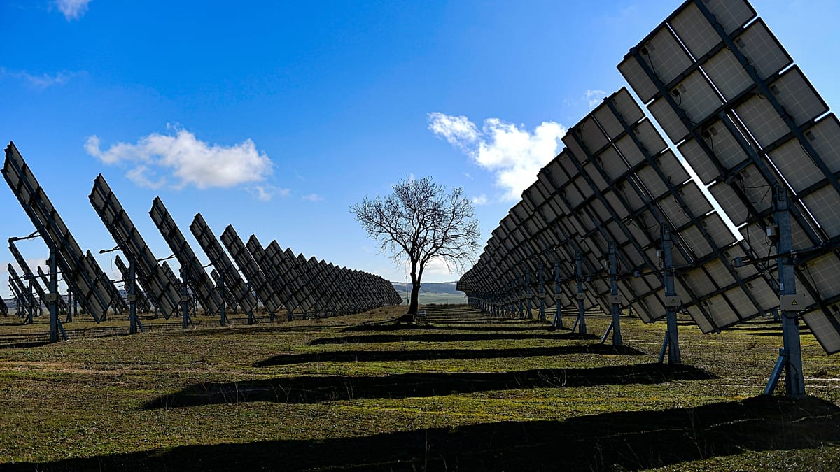 Rows of blue solar panels stretching across Spanish countryside under bright sunny sky