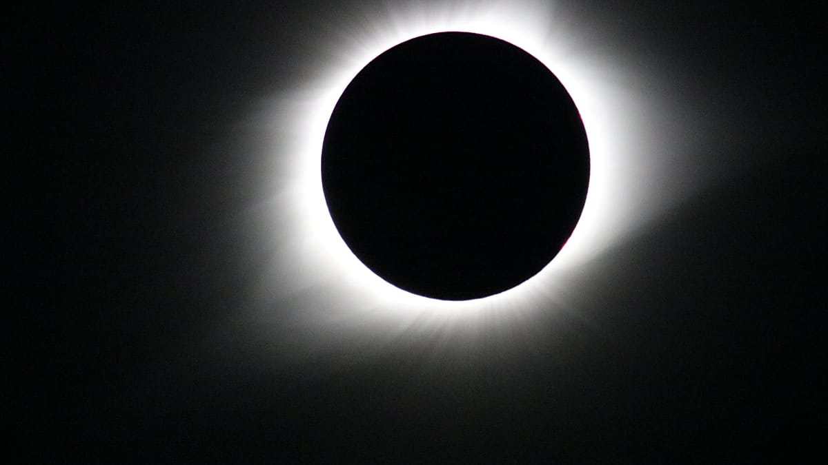 Total solar eclipse showing moon blocking sun with glowing corona visible around dark circle